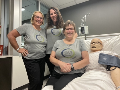 Staff pose with dummy patient in hospital bed